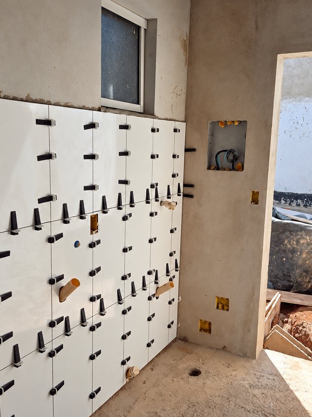 Banheiro em obra bruta, com revestimento em assentamento e espaçadores niveladores