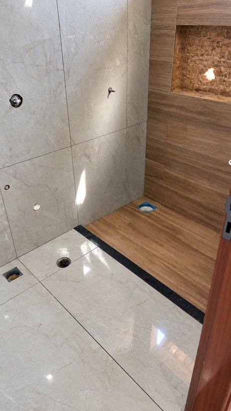 Banheiro revestido em porcelanato marmorizado polido, com faixa preta e box amadeirado